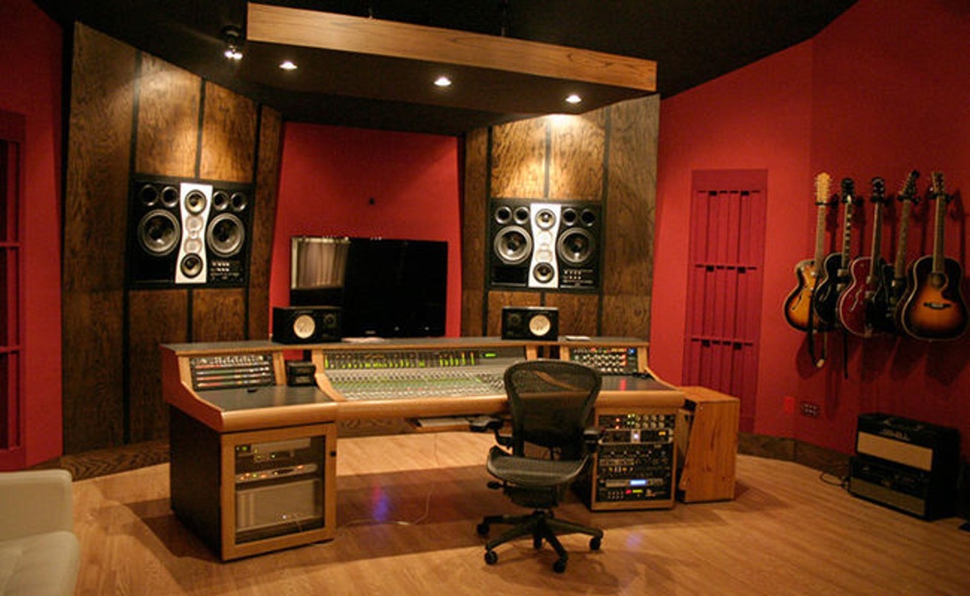 Een professionele opnamestudio met een groot mengpaneel en gitaren aan de muur, een omgeving waar een onberispelijke stroomvoorziening essentieel is.